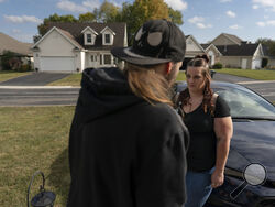 Peer support worker Jesse Johnson of the Family Resource Center looks to her client Tyler Baker as they talk in the driveway of Baker's home in Findlay, Ohio, Thursday, Oct. 12, 2023. Peer support services for people in recovery are a major component of Hancock County's strategy for addressing the opioid epidemic. (AP Photo/Carolyn Kaster)