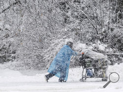 A pedestrian pushes a shopping cart on Cordova Street during a heavy snowfall, Thursday, Nov. 9, 2023 in Anchorage, Alaska. Four homeless people have died in Anchorage in the last week, underscoring the city’s ongoing struggle to house a large houseless population at the same time winter weather has returned, with more than 2 feet (0.61 meters) of snow falling within 48 hours. (Marc Lester/Anchorage Daily News via AP)