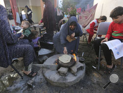 A Palestinian woman bakes bread in Rafah, Gaza Strip, Thursday, Nov. 16, 2023. (AP Photo/Hatem Ali)
