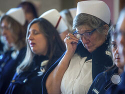 Connecticut Nurses Honor Guard member Kelly Salata, of Clinton, wipes a tear away during a vigil for Joyce Grayson at the Connecticut State Capitol's North Lobby on Tuesday, Nov. 28, 2023, in Hartford, Conn. The death of the 63-year-old mother of six is sparking renewed calls to better protect health care workers from a wave of violent attacks across the country. (Aaron Flaum/Hartford Courant via AP)