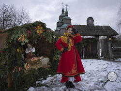 A woman dressed in national costume stands near the nativity scene to celebrate Christmas in the village of Pirogovo, outside the capital Kyiv, Ukraine, Monday, Dec. 25, 2023. (AP Photo/Efrem Lukatsky)