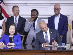 Maryland Gov. Wes Moore signs an executive order to issue more than 175,000 pardons for marijuana convictions on Monday, June 17, 2024 in Annapolis, Md. Maryland Secretary of State Susan Lee is seated left. Standing left to right are Lt. Gov. Aruna Miller, Maryland Attorney General Anthony Brown, Shiloh Jordan, Jason Ortiz, director of strategic initiatives for Last Prisoner Project and Heather Warnken, executive director of the University of Baltimore School of Law Center for Criminal Justice. (AP Phopto/B