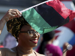 FILE - Crystal Baziel holds the Pan-African flag Monday, June 19, 2023, during Reedy Chapel A.M.E Church's annual Juneteenth Family Fun Day, in Galveston, Texas. 