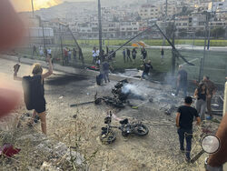 (AP Photo/Hassan Shams Residents rush to help injured children moments after a rocket attack hit a soccer field in the Druze town of Majdal Shams in the Israeli-controlled Golan Heights, Saturday.