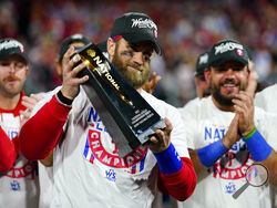 Philadelphia Phillies designated hitter Bryce Harper celebrates with the trophy after winning the baseball NL Championship Series in Game 5 against the San Diego Padres on Sunday, Oct. 23, 2022, in Philadelphia. (AP Photo/Matt Slocum)