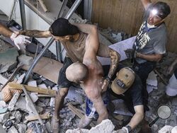 People help an injured man walk out of rubble at a sports facility destroyed after a Russian attack in Kharkiv, Ukraine, Sunday, Sept. 1 2024. (AP Photo/Yevhen Titov)