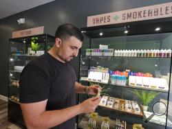 In this photo taken Thursday, March 21, 2019, Gus Dabais looks over CBD products he sells at his Sidewalk Wellness store in San Francisco. CBD oil-infused food, drinks and dietary supplements are popular even though the U.S. government says they're illegal and some local authorities have forced retailers to pull products. The confusion has California, Texas and other states moving to legalize the cannabis compound that many see as beneficial to their health. (AP Photo/Eric Risberg)