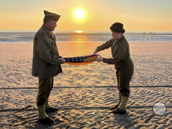 Christophe Receveur and his daughter Julie, of France, unfold an American flag he bought six month ago in Gettysburg, Penn., to mark D-Day, Thursday, June 6, 2024 on Utah Beach, Normandy. As the sun sets on the D-Day generation, it's rising again over Normandy beaches where soldiers fought and died exactly 80 years ago, kicking off intense anniversary commemorations Thursday against the backdrop of renewed war in Europe, in Ukraine. (AP Photo/John Leicester)