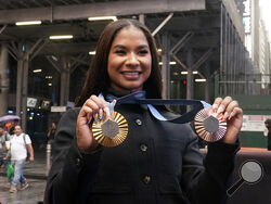 Two-time U.S. Olympic gymnast medalist Jordan Chiles shows her medals after ringing the closing bell at the Nasdaq MarketSite, in New York's Times Square, Thursday, Aug. 8, 2024. (AP Photo/Richard Drew)