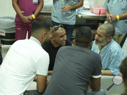 In this photo released by the Israel Prime Minister Office on Tuesday, Aug. 27, 2024, Qaid Farhan Alkadi, 52, right, who was held hostage by Hamas militants in Gaza sits in a room at the Soroka Medical Center in Beersheba, Israel. (Israel Prime Minister Office via AP)