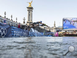 Athletes jump into the water to compete in the swimming race in the Seine river, during the mixed relay triathlon, at the 2024 Olympic Games, in Paris, France, Monday, Aug. 5, 2024. (Martin Bureau/Pool Photo via AP)