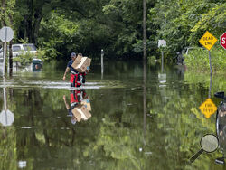 Savannah Fire Advanced Firefighters Andrew Stevenson, front, and Ron Strauss carry food to residents in the Tremont Park neighborhood that where stranded in flooding from Tropical Storm Debby, Tuesday, Aug. 6, 2024, in Savannah, Ga. (AP Photo/Stephen B. Morton)