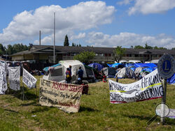 Signs line the front of an encampment of asylum-seekers mostly from Venezuela, Congo and Angola next to an unused motel owned by the county, Wednesday, June 5, 2024, in Kent, Washington. The group of about 240 asylum-seekers is asking to use the motel as temporary housing while they look for jobs and longer-term accommodations. (AP Photo/Lindsey Wasson)