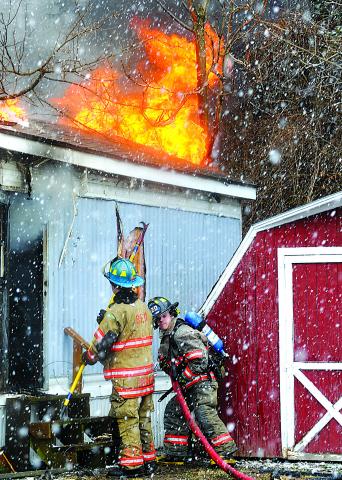 Firefighters Dennis Kuhar, left, and Aaron Roberts work to control a blaze.