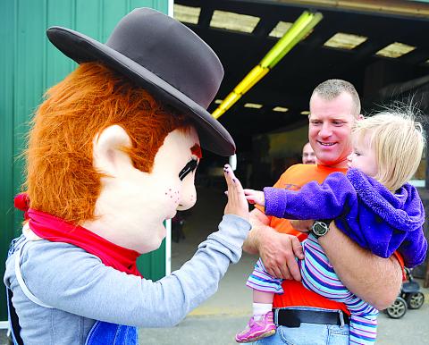 The new Bloomsburg Fair mascot, Farmer Bloom, gets a high-five from Ellie Mae Farwell, held by her father Joe Farwell Saturday at the Bloomsburg Fair. Farmer Bloom roamed the fairgrounds greeting guests.