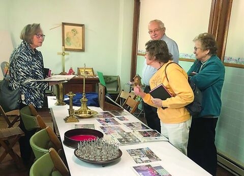 Marcia Hanley Kreischer, left, Pat Erlsten, in yellow, Corey Kreischer, in back, and Evelyn Mushalko reminisce as they look over artifacts from Centralia United Methodist Church. Erlsten holds a Bible originally given to the Centralia church in honor of her uncle.