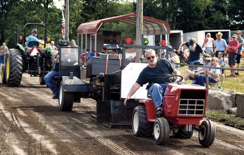 Barry Hawk, Palmyra, in photo at left, leans to one side as he helps his garden tractor to the finish line during the annual tractor pull contest at the Hobbie Fire Company carnival on Saturday