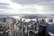 FILE - This May 20, 2015, file photo, shows New York's Financial District, foreground, the Brooklyn Bridge and East River, center, and in the distance Brooklyn as seen from the observatory at One World Trade Center. Some of the industries that have defined New York City and the Washington area will face increased competition for talent when Amazon sets up shop in their territory, with plans to hire 50,000 new workers amid the tightest job market in decades. (AP Photo/Mark Lennihan, File)