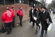 Members of the Guardian Angels, left, a volunteer safety patrol organization, stand in front of the Chabad Lubavitch World Headquarters, Monday, Dec. 30, 2019 in the Brooklyn borough of New York. The Guardian Angels and police have increased patrols in the Crown Heights neighborhood following an anti-Semitic attack on a Hanukkah celebration in Monsey, N.Y. (AP Photo/Mark Lennihan)
