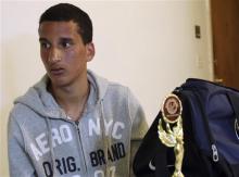 Salah Eddin Barhoum sits in his apartment in Revere, Mass., Thursday, April 18, 2013, with one of the trophies he won in an athletic competition, and the bag he was carrying on Monday near the finish line of the Boston Marathon. The 17-year-old from Morocco, whose photograph appeared on the front page of the New York Post in connection with the Boston Marathon bombings, told The Associated Press he has been scared to go outside because he worries people will blame him for Monday’s attack. (AP Photo