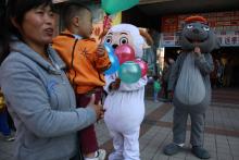 In this photo taken Sunday, Oct. 2, 2011, a woman and child gather near mascots of characters from the cartoon "Pleasant Goat and Big Big Wolf" on a street in Beijing, China. (AP Photo/Ng Han Guan)