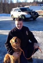 This Monday, March 3, 2014 photo released by the Alaska State Troopers shows trooper Lucas Hegg posing with his dog, Amber, a 2-year-old golden retriever. A 52-year-old Alaska man, Otis Orth, says Amber saved his life after a snowmobile crash. (AP Photo/Alaska State Troopers) 