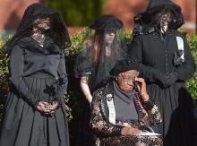 In this Saturday, Dec. 8, 2012 photo, members of the N.C. Society of the Order of the Black Rose surround Mattie Rice during a ceremony honoring 10 black men, nine of whom were slaves, who served in the Confederate Army, outside the Old County Courthouse in Monroe, N.C. (AP Photo/The Charlotte Observer, Todd Sumlin)