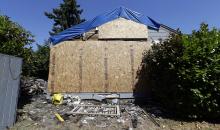 Debris from a fire remains in the yard next to the now boarded-up house where the night before a man used a can of spray paint and a lighter as a makeshift blowtorch to kill a spider, Wednesday, July 16, 2014, in Seattle. The makeshift blowtorch started a blaze that caused $60,000 worth of damage, Seattle fire officials said Wednesday. The man and his mother got out of the house, and no injuries were reported. (AP Photo/Elaine Thompson) 