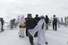A couple walk off together after joining eighty-seven other couples who gathered in a snow storm atop a mountain to get married or renew their vows.