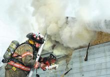 Millville firefighter Steve Brown uses a chainsaw to cut into the cathedral ceiling at this home on at 98 Rhodomoyer Road, Mount Pleasant Township Sunday morning. Press Enterprise/Keith Haupt