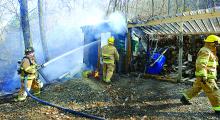 Main Township firefighter Jonathan Broadt, left, douses flames in a small shed near a home in Wonderview, Main Township Saturday afternoon. The shed and woods nearby burned. (Press Enterprise/MJ Mahon)