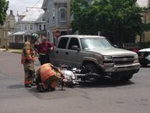 Firefighters, foreground, examine a motorcycle wreck while the pickup truck's driver, Bob Crane, stands at the back of his vehicle.