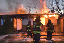 Firefighters stand in the front yard of the home at 40 First Ave. in Briar Creek borough on Tuesday while waiting for tankers to arrive to supply water to put out the fire.