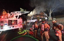 Millville’s rapid intervention team stands ready at the rear of Espy’s ladder truck as firefighters from several department battle a fire at 717 Fowlersville Road in North Centre Township Monday evening.