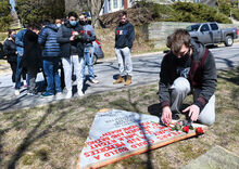 Christopher Herman, right, places a rose and a candle at the site of a 2000 fire that killed three members of the TKE fraternity on Fourth Street in Bloomsburg.