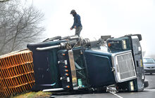 The driver climbs out of the cab of his tractor trailer after rolling it into its side. The accident happened while he was exiting eastbound Interstate 80 onto State Route 11 Friday morning.