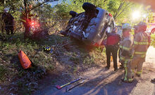 Rescue personnel use rope lines to secure the undercarriage of a Ford Escape to a tree as others enter the vehicle through the rear hatch as the Escape rests on its passenger side. The vehicle veered off Lightstreet Road in Scott Township and into a group of bushes along a driveway at 1101 Lightstreet Road on Wednesday night. 