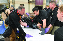 The Joint Program Executive Office for Chemical, Biological, Radiological and Nuclear Defense medical team members move one of the entry team personnel onto a stretcher while simulating a person injured during Thursday’s training at Commonwealth University-Bloomsburg. 