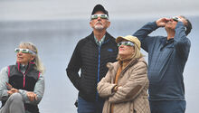 From left, Luci Callahan, Paul Callahan, Linda Lispi and Gene Lispi, all of the Back Mountain, get a glimpse of the partial solar eclipse as they sun can be seen through the clouds as they view it from next to Lake Jean at Ricketts Glen State Park Monday afternoon. 