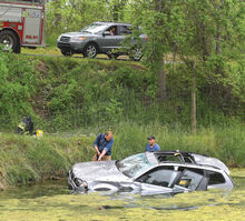 Alan Delieto, right, and Dylan Briggs, Nescopeck Fire Company assistant chiefs, enter the water near this vehicle that rolled down an embankment. It stopped in a pond at 1354 Zenith Road in Nescopeck Township Tuesday morning.