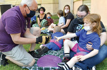 Bill Fait, left, holds a toad as Cayden Casner reaches out for it while students from the Danville Primary School make a visit to the garden at the Thomas Beaver Free Library in Danville Friday. 