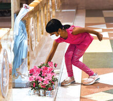 St. Cyril kindergartener Anjali Agarwal places flowers at the feet of a statue of the Blessed Mother inside the Basilica at St Cyril’s Wednesday morning. The May Crowning dates back to when the Basilica was an all-girls high school.