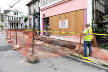 Danville Public Works employrr Bruce Earlston places an orange fence around the front of the former Karen Gronsky Dance Studio Thursday morning on Center Street in Danville. The borough will be opening up the street to traffic today.  Flames destroyed the building in late May.