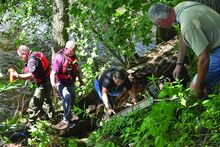 Bloomsburg Fire Lt. Gary Harner, right, and chief Scott McBride, second from left, are ready to assist as Gale Levine works her way up a ladder on the bank of Fishing Creek after being helped from the swollen creek Monday afternoon. Deputy chief John Mahon pulls in rope line they used during the incident, at left.