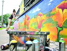 Jules Muck, who paints under the name Muck Rock, from Venice, California spray paints flowers on a wall of the Intoxicology Department bar in Berwick on Tuesday as part of her tour around the country.