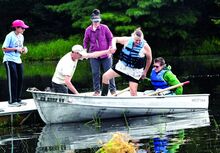 Graham Goodman, right, 17, Wyoming, holds his mom Allegra Goodman’s hand as he and volunteer Paul Zajac help her into the rowboat on Sunset Lake at Camp Louise during Family Autism Day on Sunday afternoon. Looking on are lifeguard Sabrina Sepulveda, left, and volunteer Victoria Frederick. The Friends of Camp Louise received a grant from Autism Awareness of Northeast Pennsylvania to hold the special day at Camp Louise Center for Outdoor Recreation and Education. 