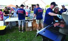 Bloomsburg Fire Chief Scott McBride and his wife Nancy McBride work together while manning the grill during Tuesday evening’s National Night Out at the Bloomsburg Fairgrounds. The fire department was handing out hot dogs, drinks and chips at the event. 