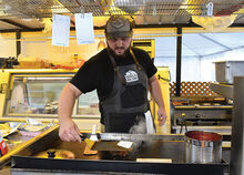 Nick Oman cooks up a cheesesteak at his family’s stand, The Farmhouse Catering Co., Thursday which is set up at B Ave. near the Leonard Street gate on the Bloomsburg Fairgrounds. 