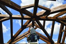 Chris Hogue, a crew foreman and electrician with Central PA Timber Frames, creates a hole in the center of one of their structures being built on the Bloomsburg Fairgrounds Tuesday. 