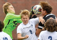 Muncy’s goalkeeper Eli Slamka, left, reaches past teammate Brock Minier, center, to hit the ball into the face of Benton’s James DiLossi as it drops in front of the goal during the first half of Wednesday afternoon’s game in Benton.